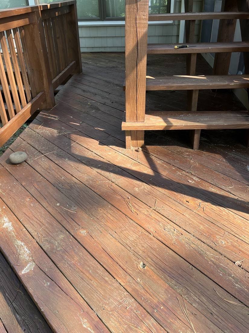 Before — gray weathered deck boards and stairs